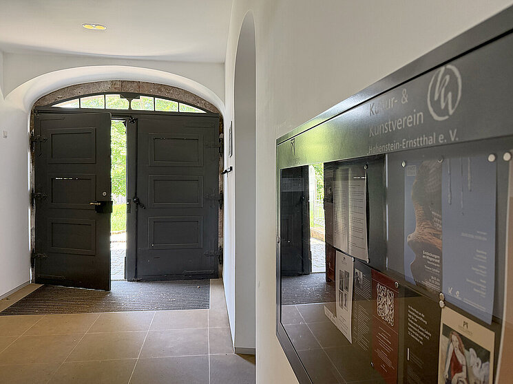 Eingangsbereich der Kleinen Galerie Hohenstein-Ernstthal mit historischem Torbogen, geöffneten dunklen Holztüren und Informationstafel des Kultur- und Kunstvereins.