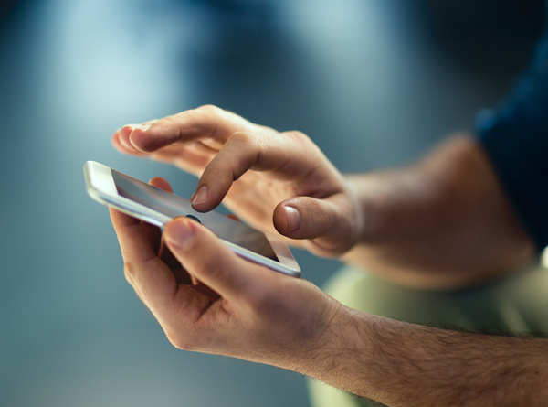 Nahaufnahme einer Person, die ein Smartphone in beiden Händen hält und mit einem Finger den Touchscreen bedient
